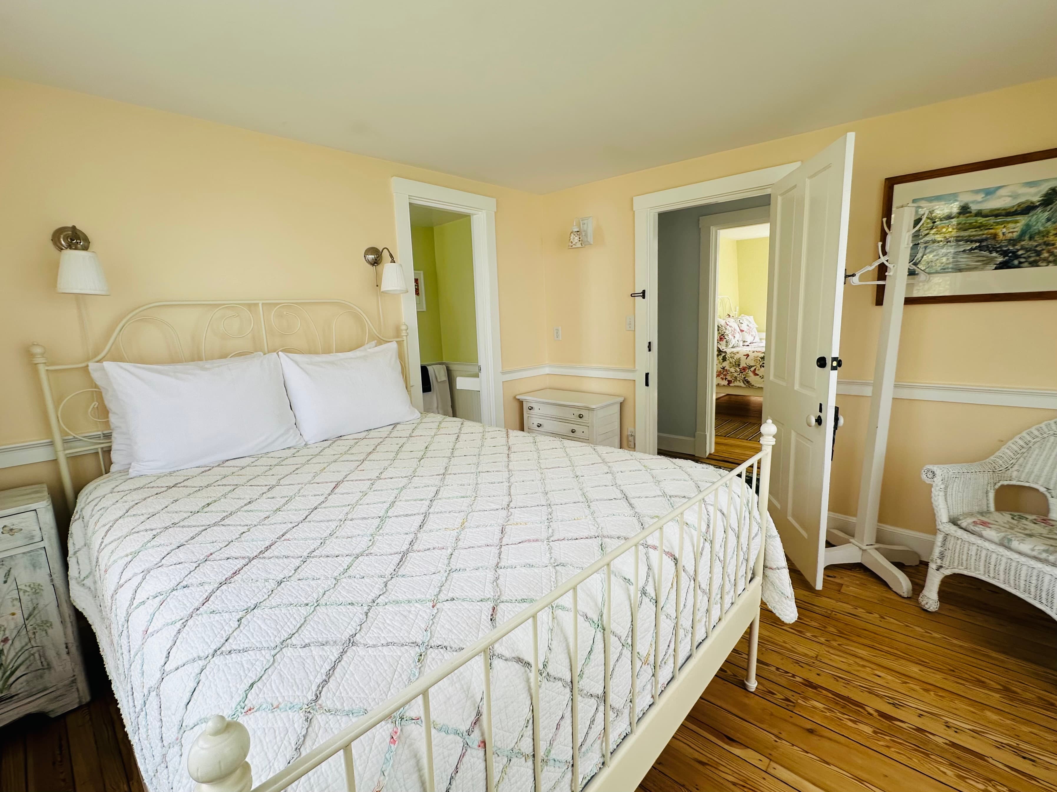 Cozy bedroom with a white metal bed, two doors, and light-colored walls.