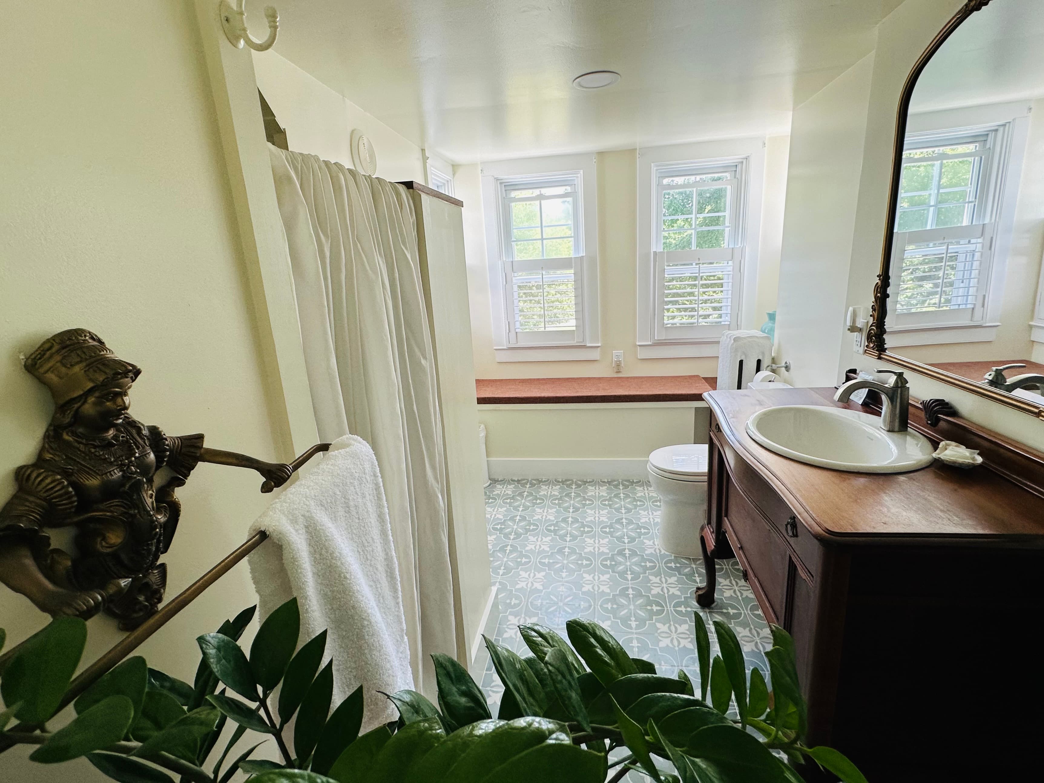 Bright bathroom featuring a vintage vanity, fresh towels, and potted greenery.
