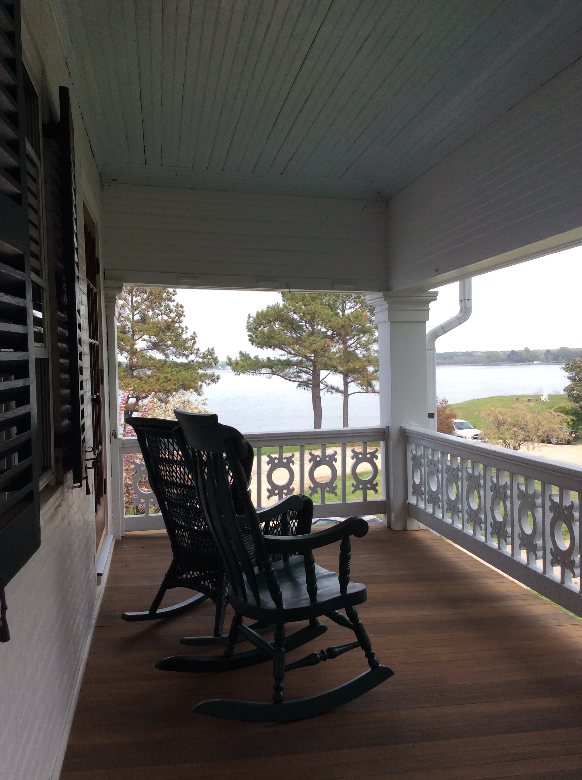 A porch with two rocking chairs overlooking a lake and trees.