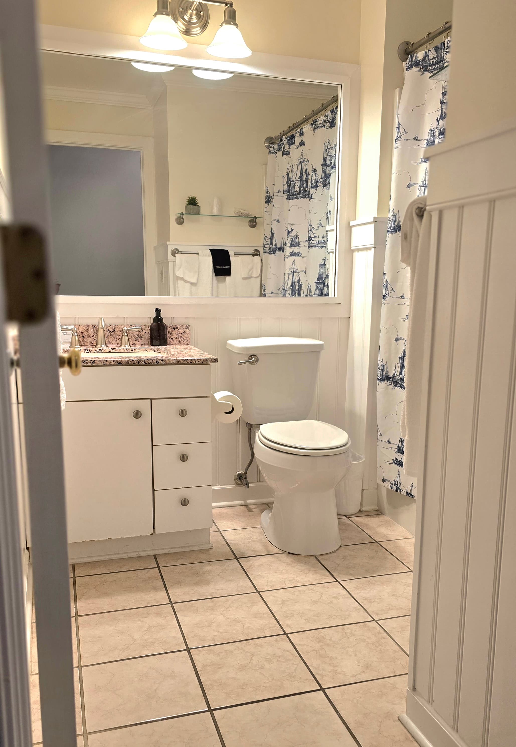 A clean bathroom featuring a white toilet, a granite countertop, and a patterned shower curtain.
