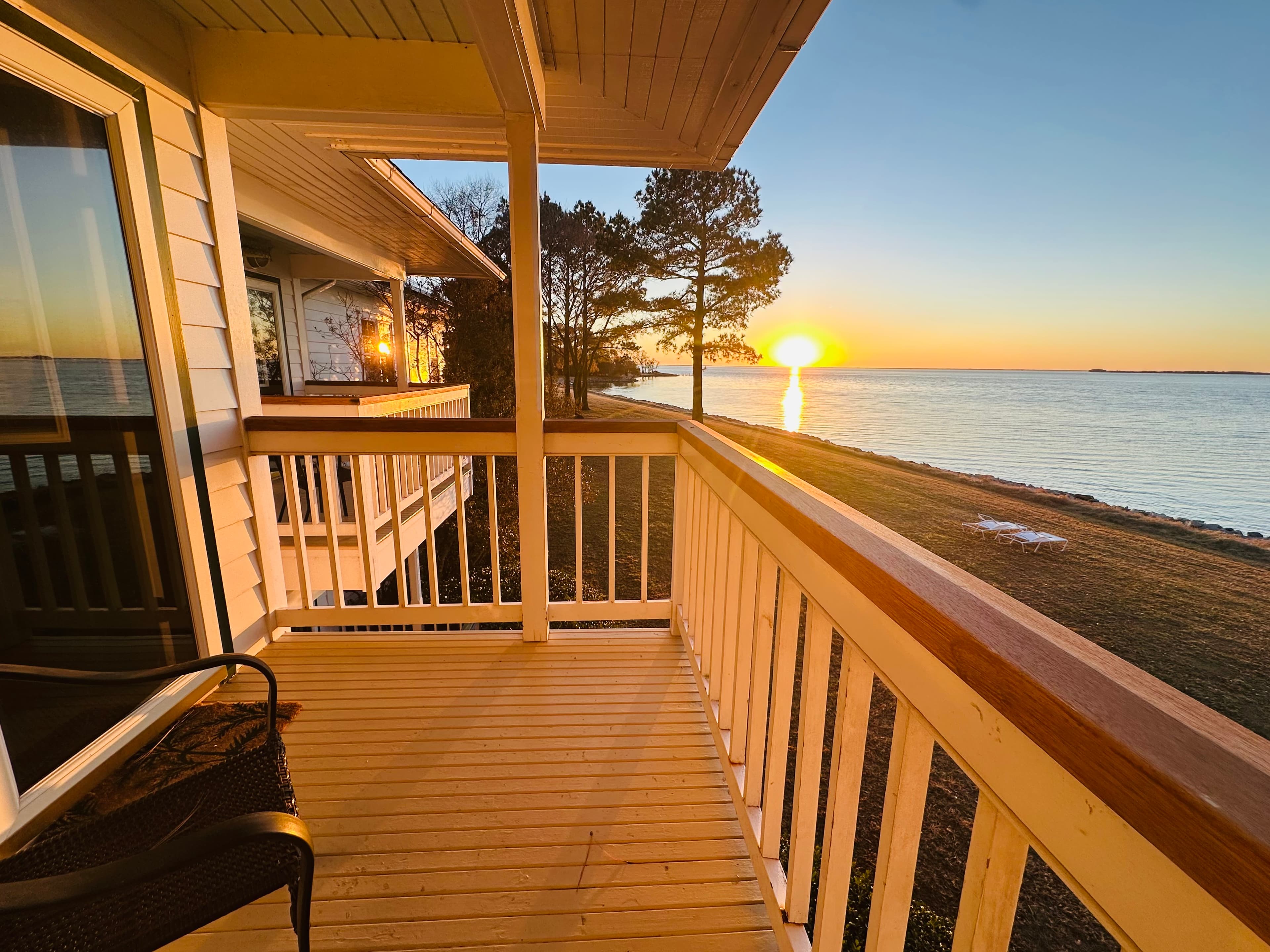 A sunset view over a calm body of water from a wooden balcony.