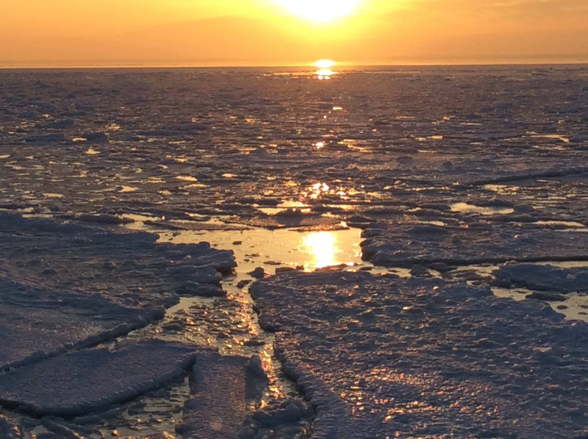 Sunset glimmers over a frozen, icy landscape.