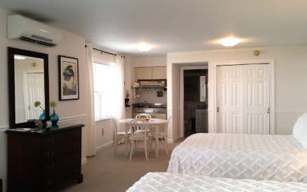 A spacious hotel room featuring two beds, a kitchenette, and a small dining area.
