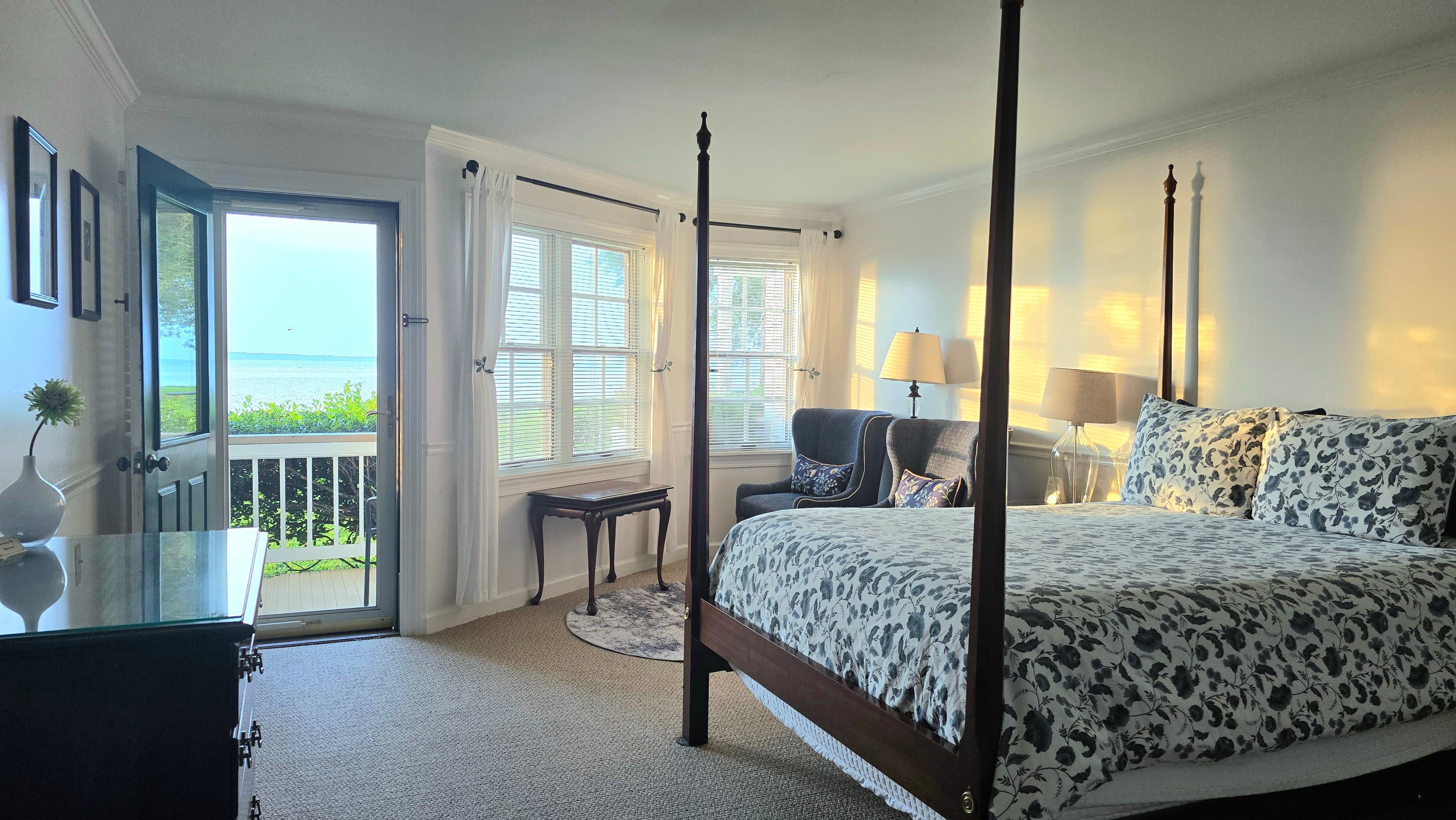 Cozy bedroom with a four-poster bed, a window view of the outdoors, and soft lighting.