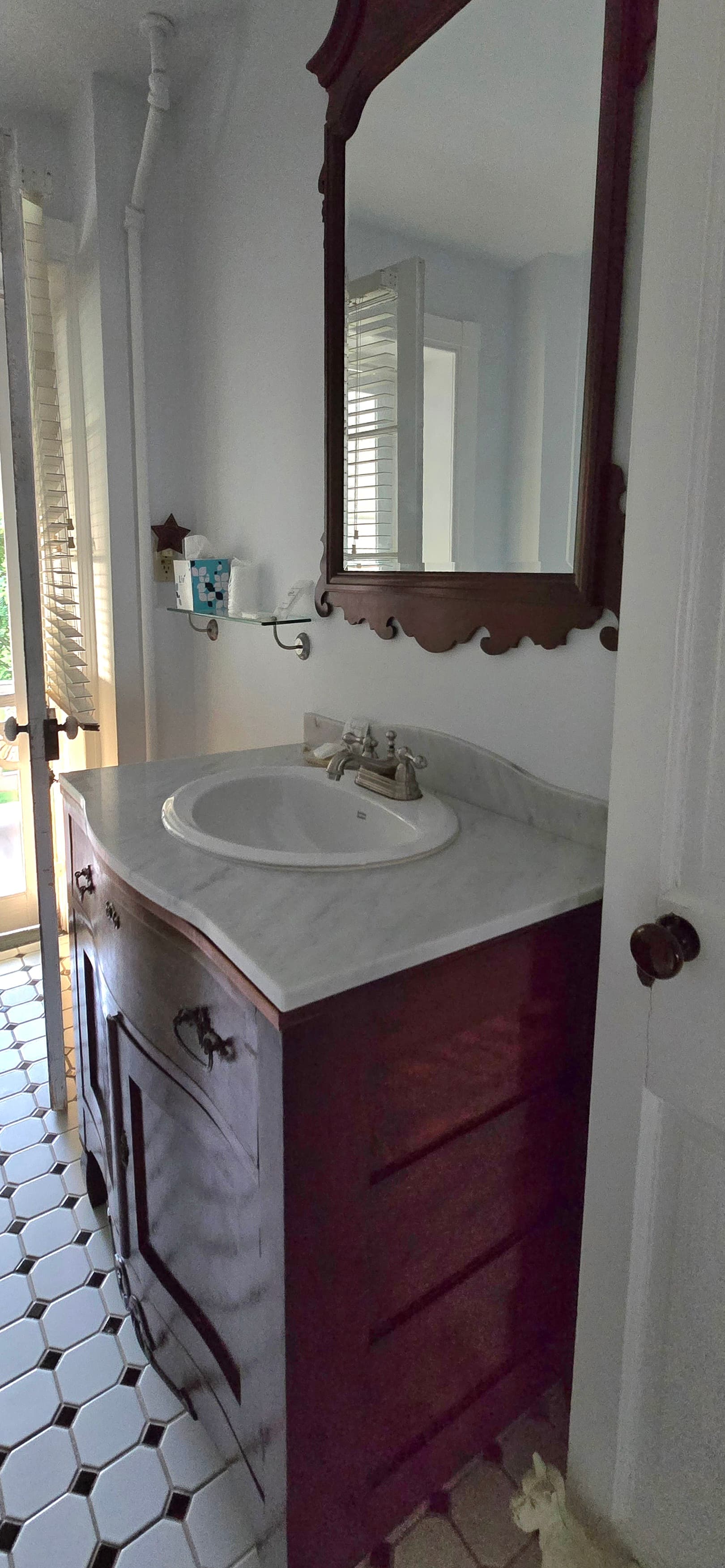 A bathroom featuring a wooden vanity, marble countertop, and a large mirror above the sink.