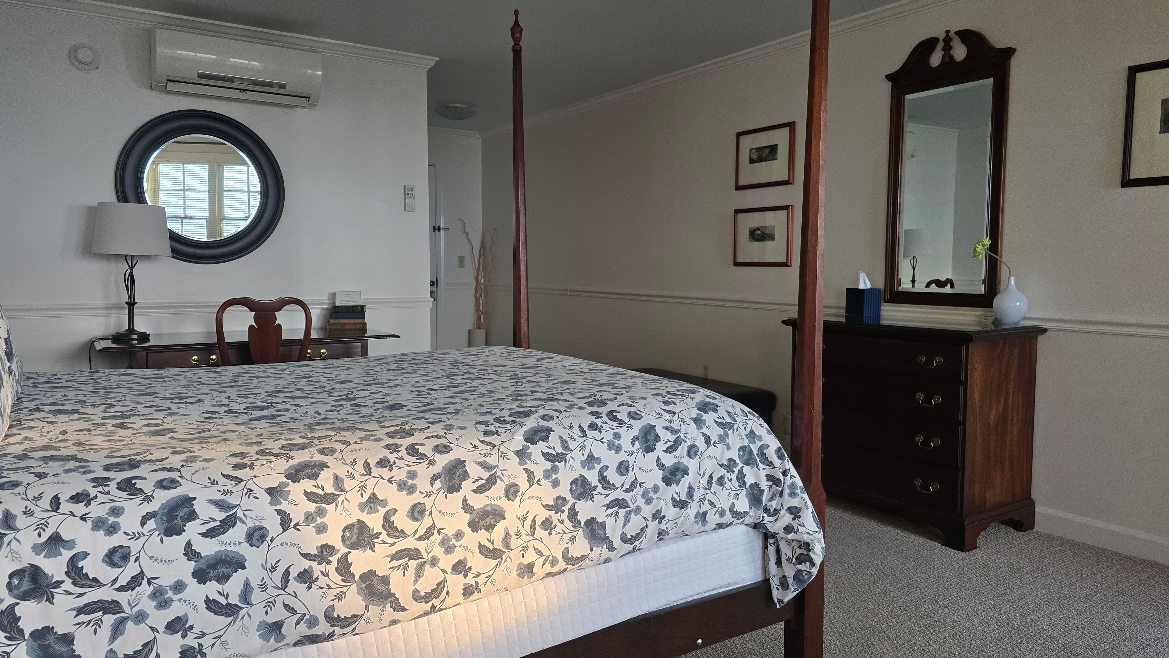 Cozy bedroom featuring a four-poster bed, a dresser, and a round mirror on the wall.