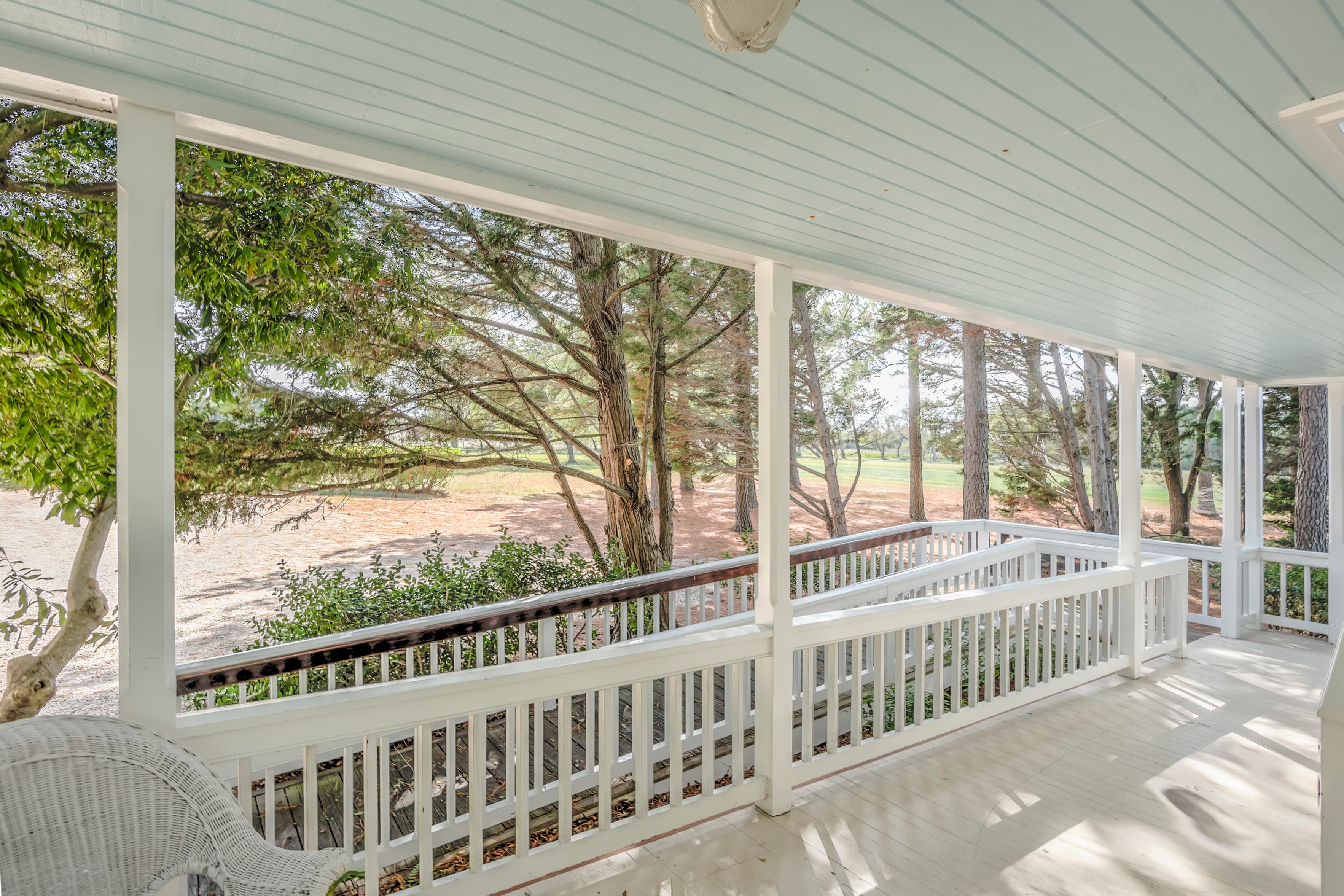 A view from a porch surrounded by trees and open landscape.