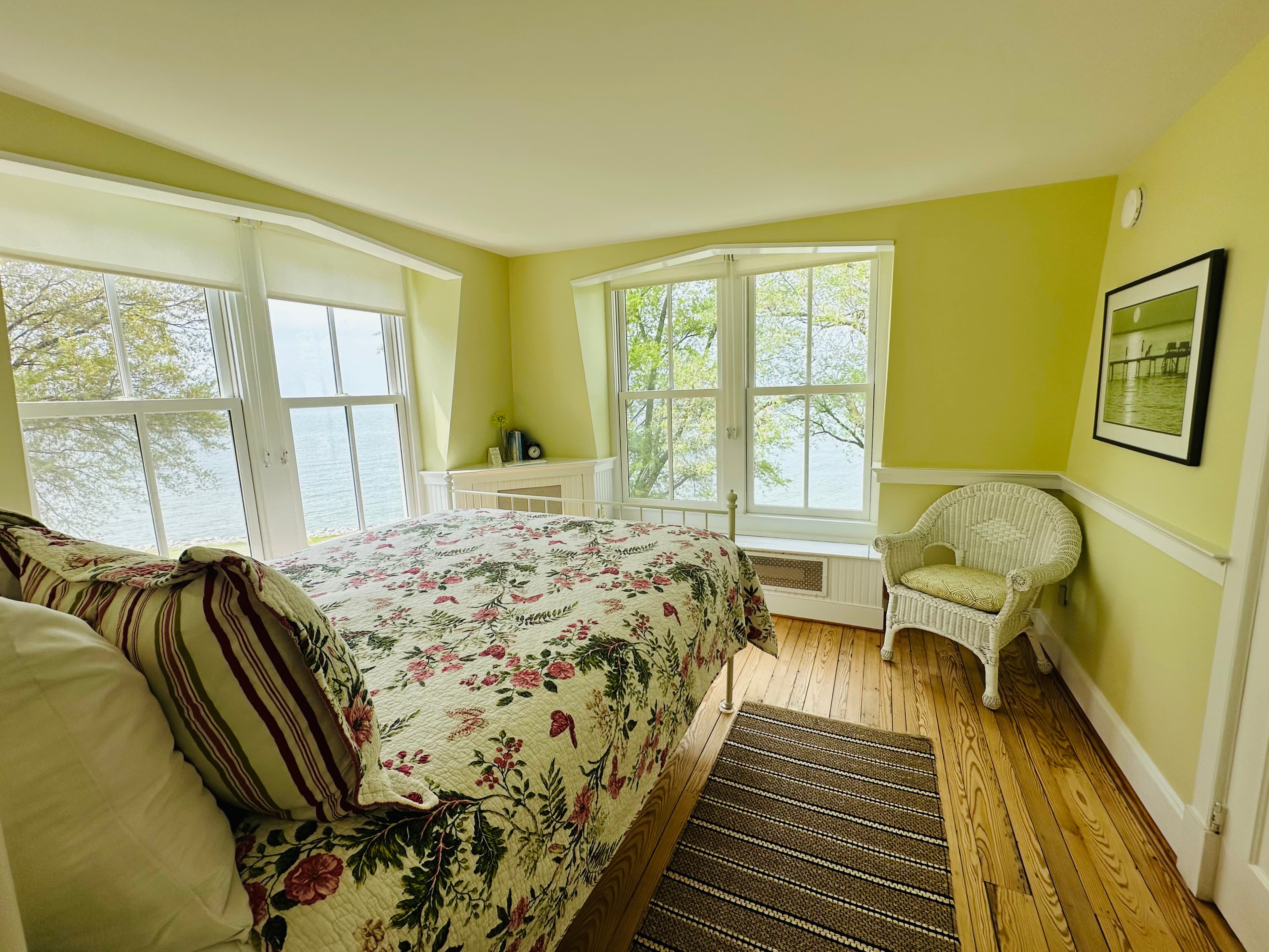 A cozy bedroom with a floral bedspread and large windows overlooking a scenic view.