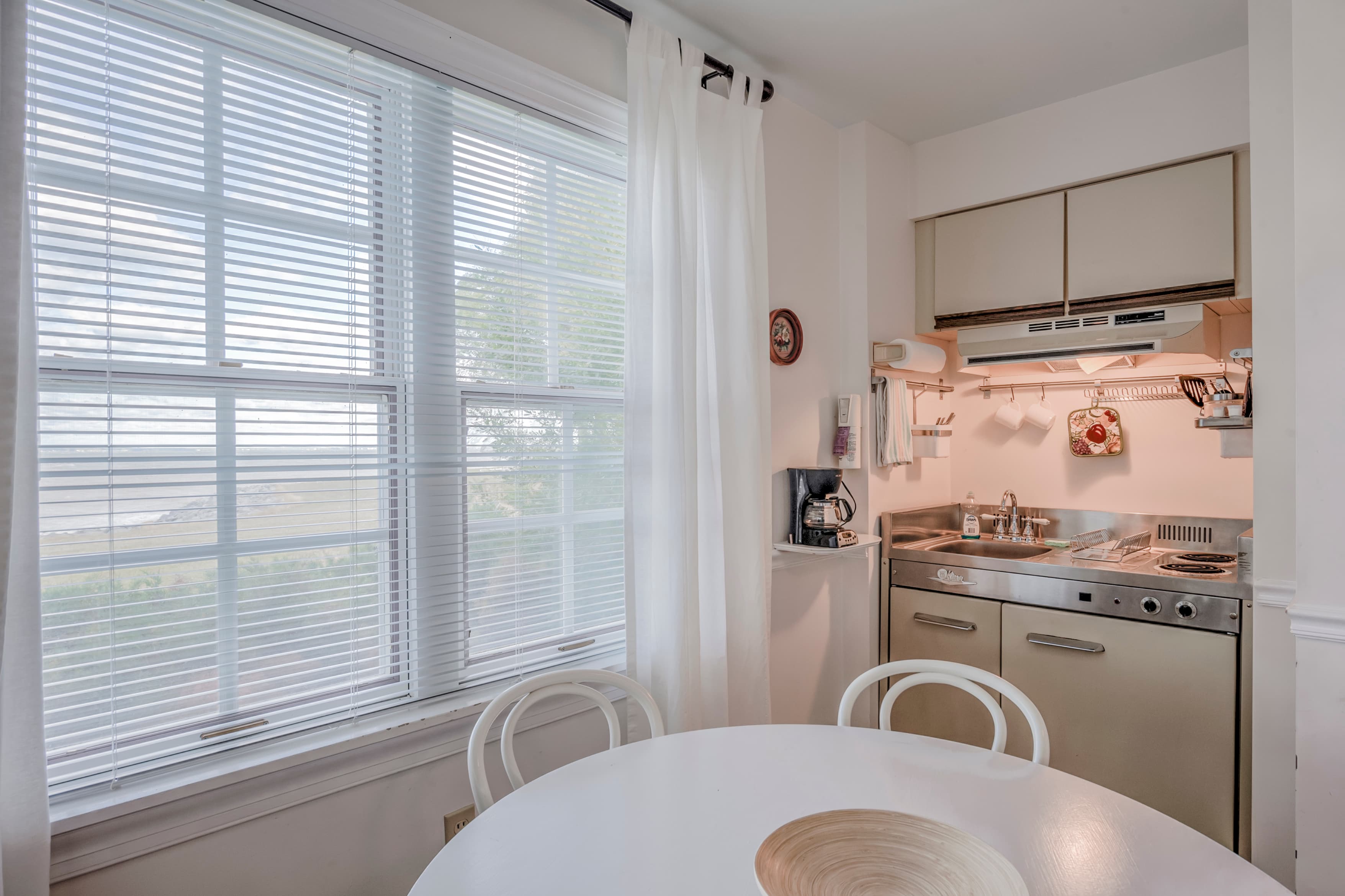 Bright kitchen with a round dining table, two chairs, and a compact cooking area by a window.
