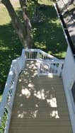 Aerial view of a wooden deck with white railings and shadows cast by nearby trees.