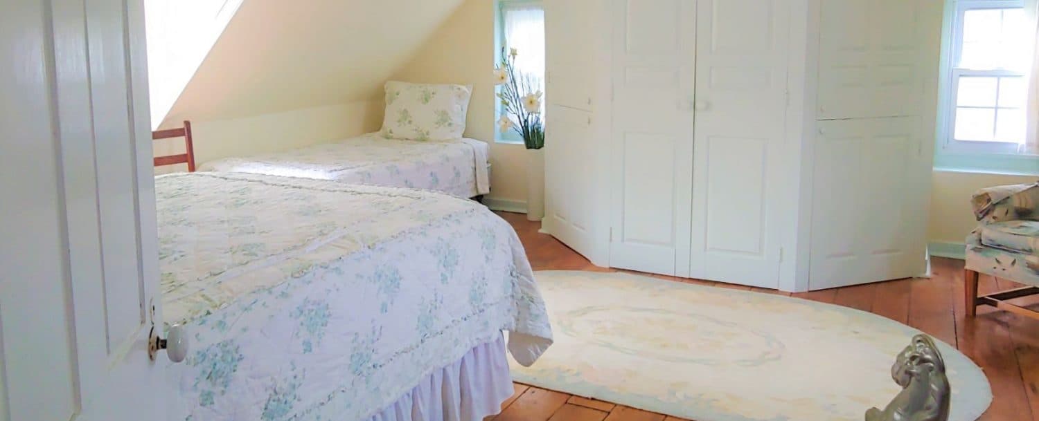 Bright, cozy bedroom with two twin beds, a decorative rug, and a set of double doors.