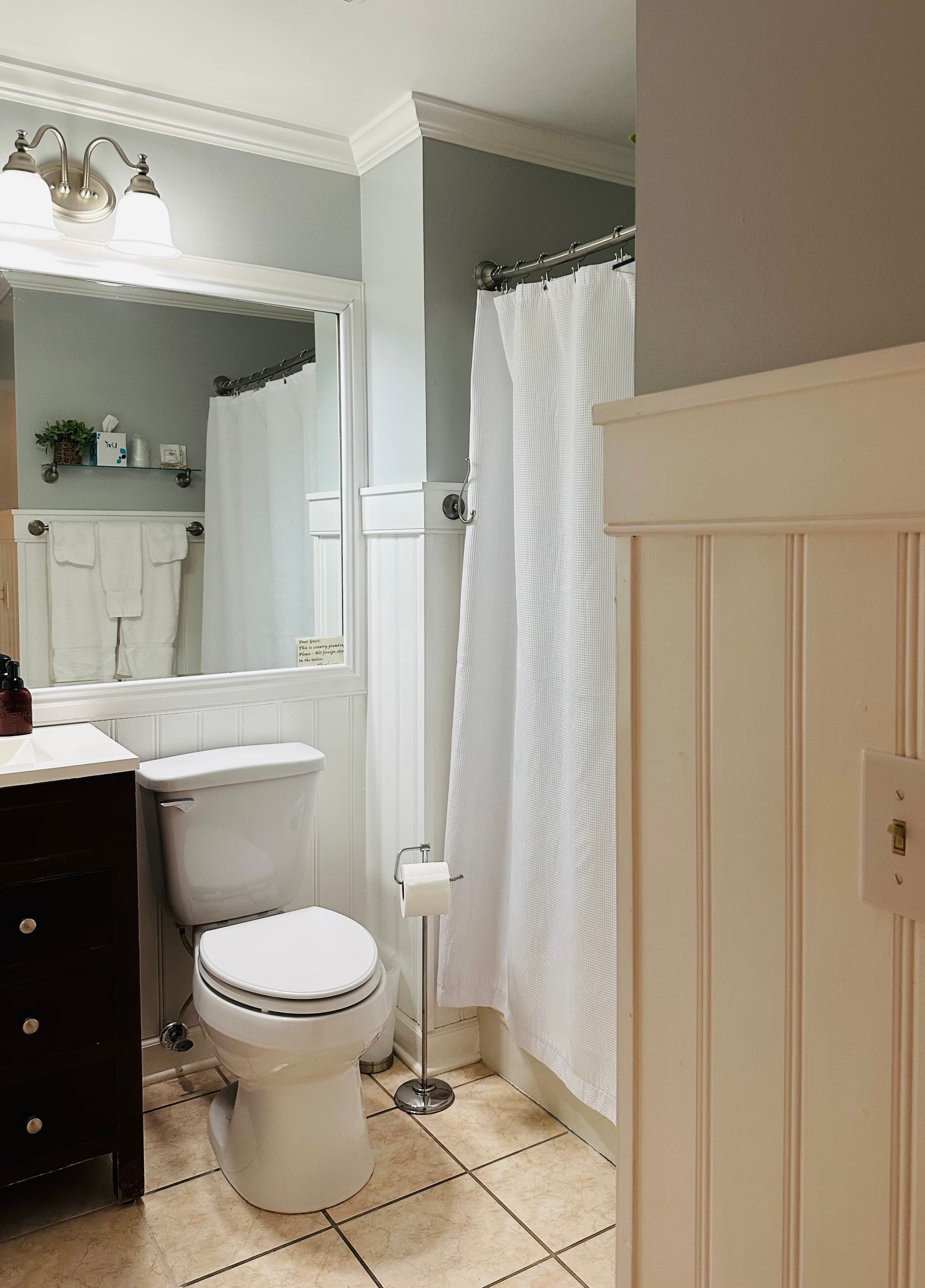 A bright, clean bathroom featuring white towels, a toilet, and a shower curtain.