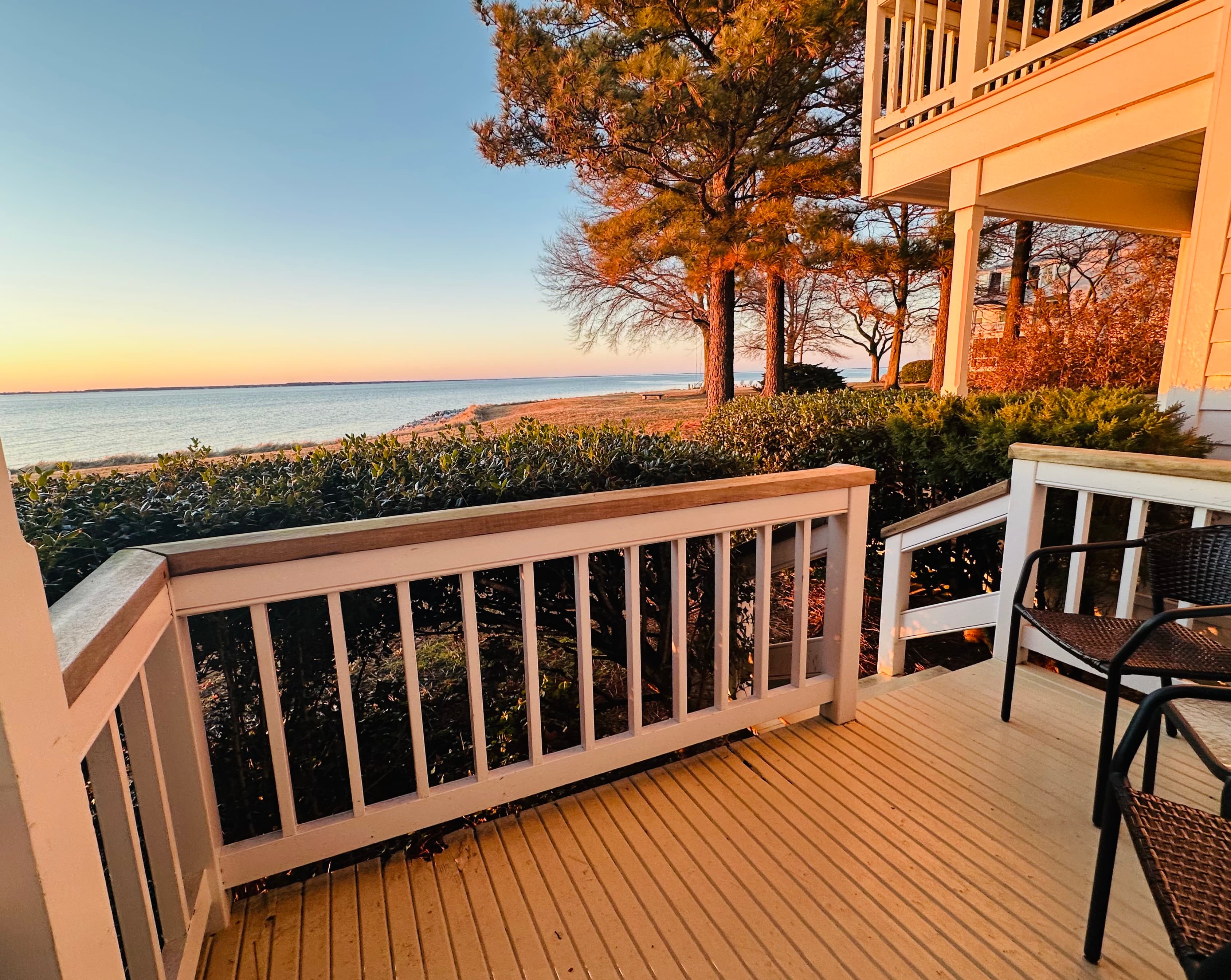 A peaceful view from a porch overlooking the water at sunset.
